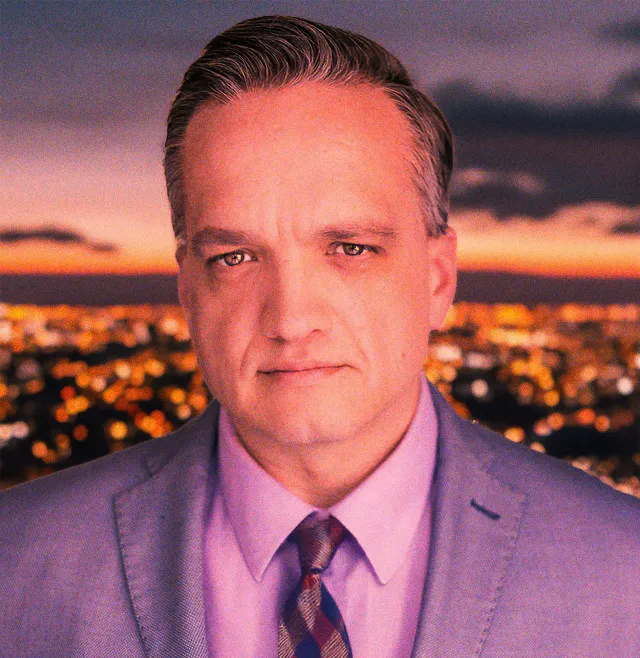 Caleb Mills Stewart in a suit against a twilight cityscape (presskit precleared).